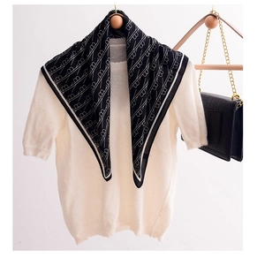 Close-up of a black and white geometric pattern silk scarf styled with a white sweater