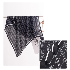 Detail view of black silk scarf with white monogram print and diagonal twill texture