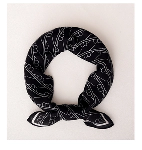 Detailed close-up of a black silk scarf featuring white geometric patterns and letters