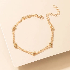 Close-up of double-layer gold anklet with small beads and adjustable lobster clasp detail