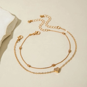 Detail of layered gold ankle bracelets with heart pendant and adjustable clasp for women