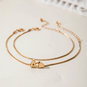 Detail of gold layered anklet with initial A and heart charm on dainty box chain