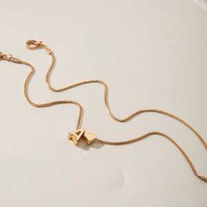 Close-up of golden box chain necklace with letter A and heart pendants and lobster clasp