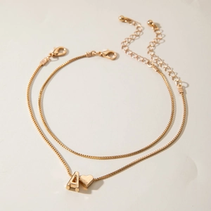 Close-up of double-layer gold anklet with letter A and heart charms on box chain