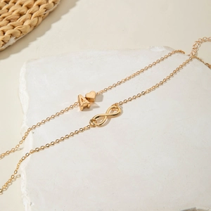 Detail of gold layered anklet featuring initial A, heart, and infinity charms on stone