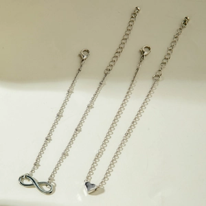 Detailed view of silver infinity and heart charms on adjustable link chains