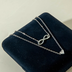 Macro detail of silver infinity and heart pendant on a multi-layer luxury necklace
