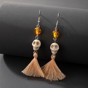 Détail macro de boucles d'oreilles tête de mort avec perles ambre et longs pompons