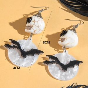 Détail de boucles d'oreilles d'Halloween avec crâne et chauve-souris sur fond jaune