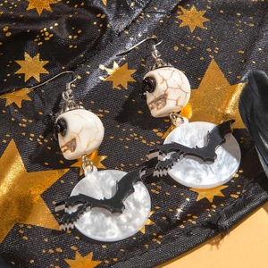Détail de boucles d'oreilles Halloween avec perles tête de mort et silhouette de chauve-souris