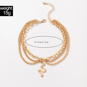 Detail showing the layered golden chain design and snake relief pendant of the anklet