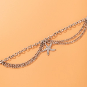 Macro detail of silver multi-layered chain anklet featuring a textured starfish charm