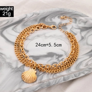 Detailed view of triple-layer gold anklet with shell pendant and adjustable chain links