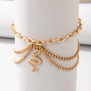 Detail of layered gold ankle chain with textured snake pendant on display stand