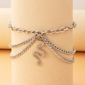 Detailed macro view of layered silver metal anklet featuring a textured snake charm pendant