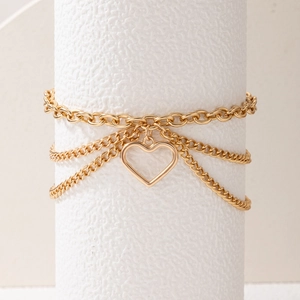 Close-up of gold layered anklet featuring triple chains and a hollow heart pendant