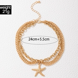 Detailed shot of triple layered gold anklet featuring a textured starfish charm and lobster clasp