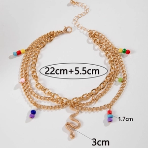 Detailed view of triple-layered gold anklet featuring a snake pendant and colorful beads
