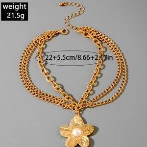 Detailed view of triple-layered gold anklet featuring flower pendant with pearl center