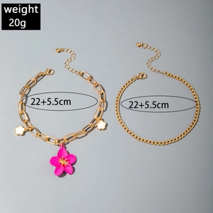 Detail of gold chain anklets set with pink hibiscus flower charm and lobster clasp