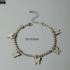 Close-up of a layered silver butterfly anklet featuring sparkling rhinestones and charms