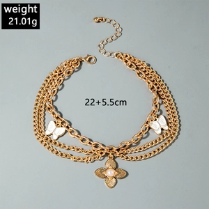 Detailed view of triple-layered golden chain anklet with butterfly and flower pendants