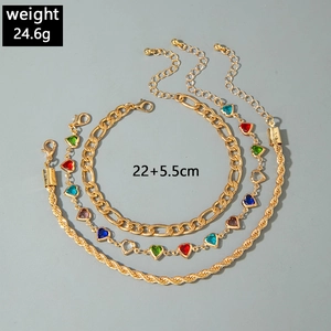 Detailed view of triple-layered gold anklets with colorful heart charms and Figaro chain