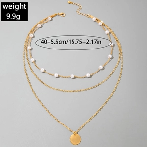 Détail du collier doré à trois rangs orné de perles et d'un pendentif métallique