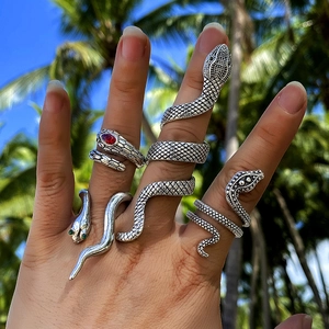 Exaggerated snake-shaped rings set with red and green gemstones in vintage silver