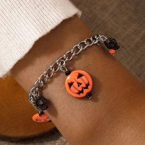 Halloween bracelet with orange pumpkin and black skull charms on a silver metal chain
