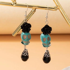 Détails macro de boucles d'oreilles tête de mort avec rose noire et goutte facettée