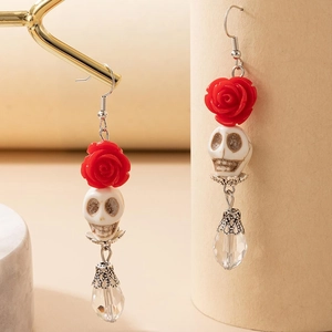 Détail de boucles d'oreilles gothiques avec rose rouge, crâne et gouttes de cristal facetté