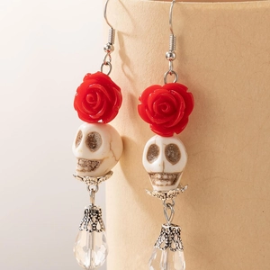 Détail de boucles d'oreilles gothiques avec rose rouge, crâne blanc et goutte cristal