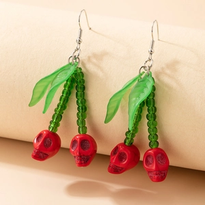 Détail de boucles d'oreilles cerises gothiques avec crânes rouges et perles vertes
