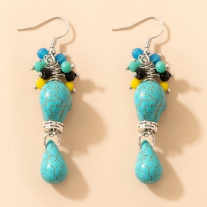 Détail de boucles d'oreilles bohèmes en turquoise avec perles argentées et crochets