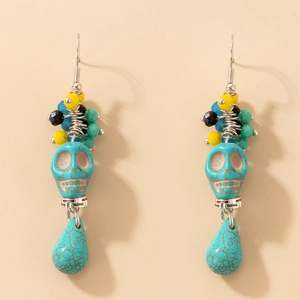 Gros plan sur boucles d'oreilles tête de mort turquoise avec perles colorées Halloween