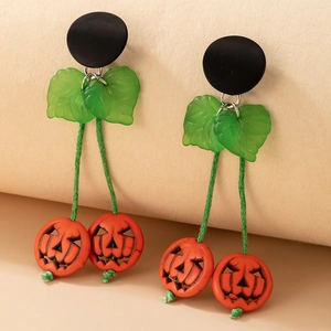 Détail de boucles d'oreilles citrouille Halloween avec clous noirs et visages sculptés orange