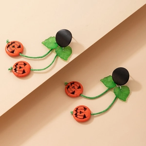 Détail de boucles d'oreilles citrouille d'Halloween avec feuilles vertes et citrouilles