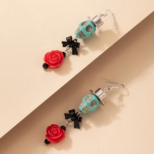 Détail de boucles d'oreilles tête de mort Halloween avec nœud noir et rose rouge