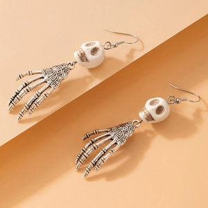 Gros plan de boucles d'oreilles tête de mort argentées avec mains d'os pour Halloween