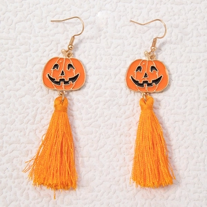 Détail de boucles d'oreilles citrouille d'Halloween avec émail et pompons orange