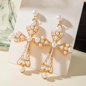 Vue détaillée de boucles d'oreilles croix dorées ornées de perles sur carte blanche