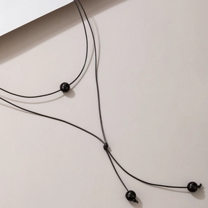 Detail of handmade black cord Y-necklace with polished beads and bohemian knot detail