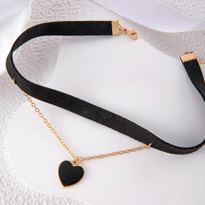 Detail of black velvet choker featuring golden chain with black enamel heart pendant