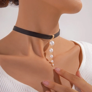 Minimalist black velvet choker with five gradient pearls hanging on a gold hook