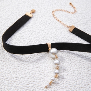 Detail of black velvet choker with graduated white pearl charms and gold clasp