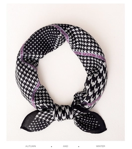 Detailed texture of black houndstooth silk scarf with modern purple brand ribbon accents