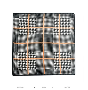 Close-up of black and white houndstooth silk scarf with orange stripe and fine stitching