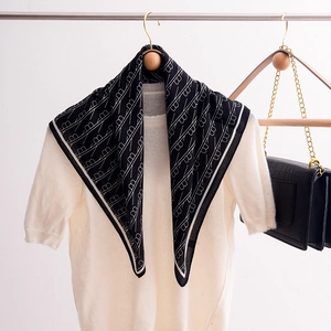 Elegant black and white geometric pattern silk scarf styled on a white knit sweater