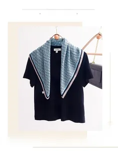 Close-up of blue silk square scarf with ring pattern draped on a black tee over a hanger